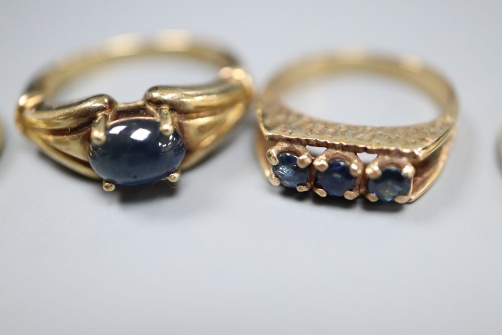 An 18ct gold, emerald and diamond asymmetric ring, an 18ct channel-set sapphire and diamond half-eternity ring and two 9ct rings